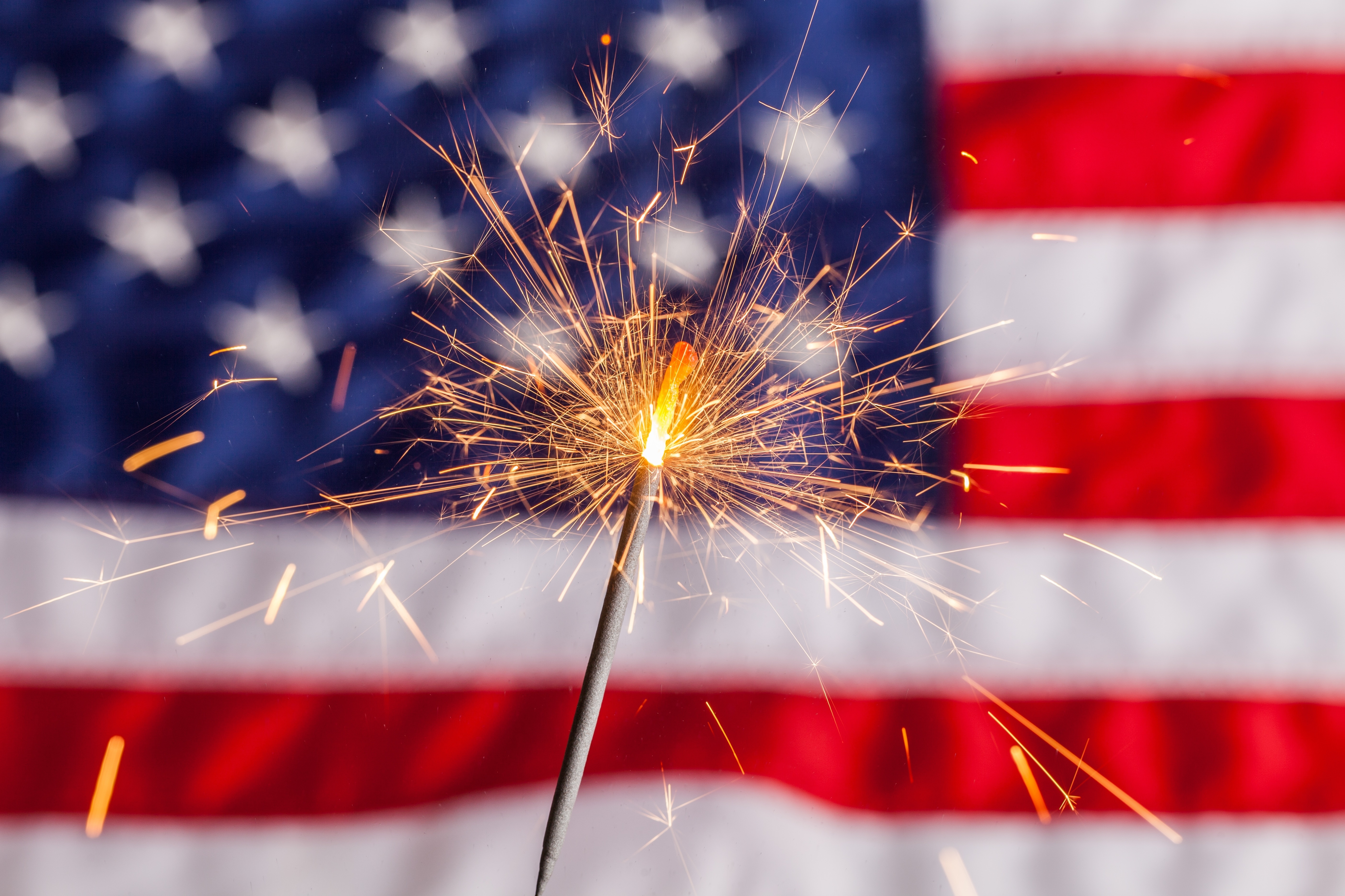 blog image of a sparkler in front of an american flag; blog title: Enjoy A Safe and Fun Fourth of July at Your Apartment